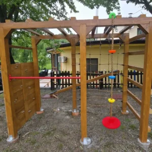 Drveni dječji poligon s penjalicom, konopcem, visećim diskovima i mrežastim zidom za penjanje na vanjskoj površini.